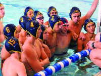 Boys’ Varsity Water Polo huddles around Assistant Coach Selena Gell.