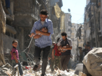 Syrian men carry  children through rubble in Aleppo in September 2016.
